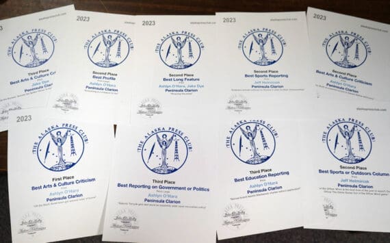 Alaska Press Club awards won by Ashlyn O’Hara, Jeff Helminiak and Jake Dye are splayed on a desk in the Peninsula Clarion’s newsroom in Kenai, Alaska, on Monday, April 22, 2024. (Jake Dye/Peninsula Clarion)