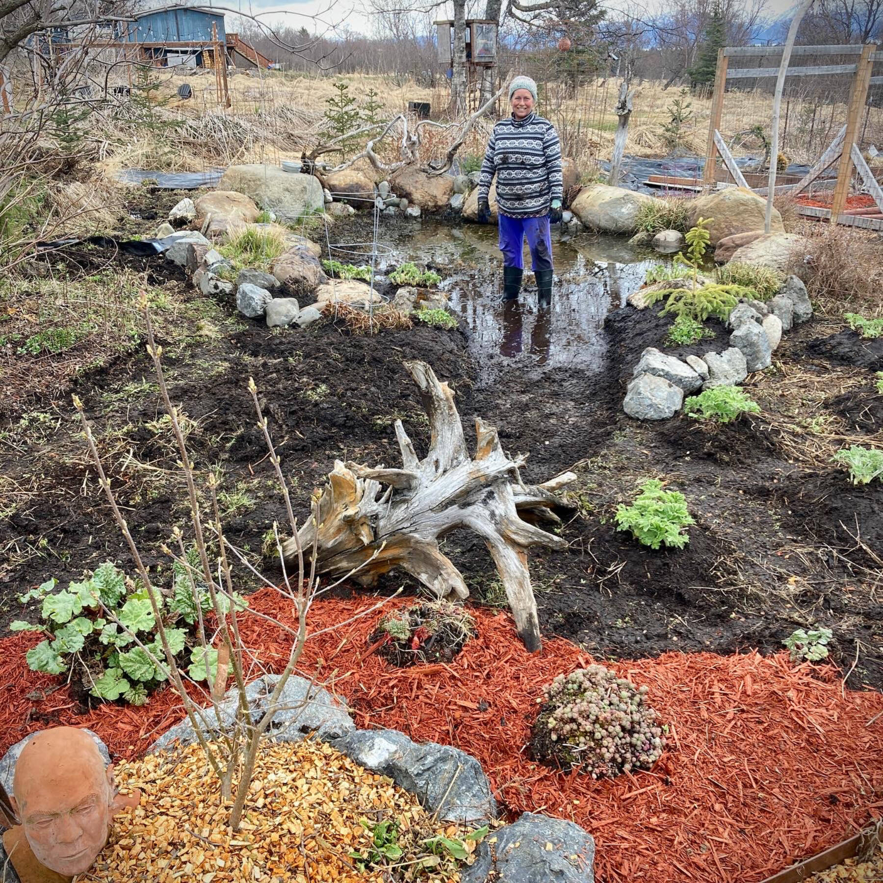 Homer artist Torie Rhyan stands in a self-dug pond, which she finished in the late fall of 2023 and created to attract more birds and pollinators to her yard in Homer, Alaska. Photo provided by Torie Rhyan