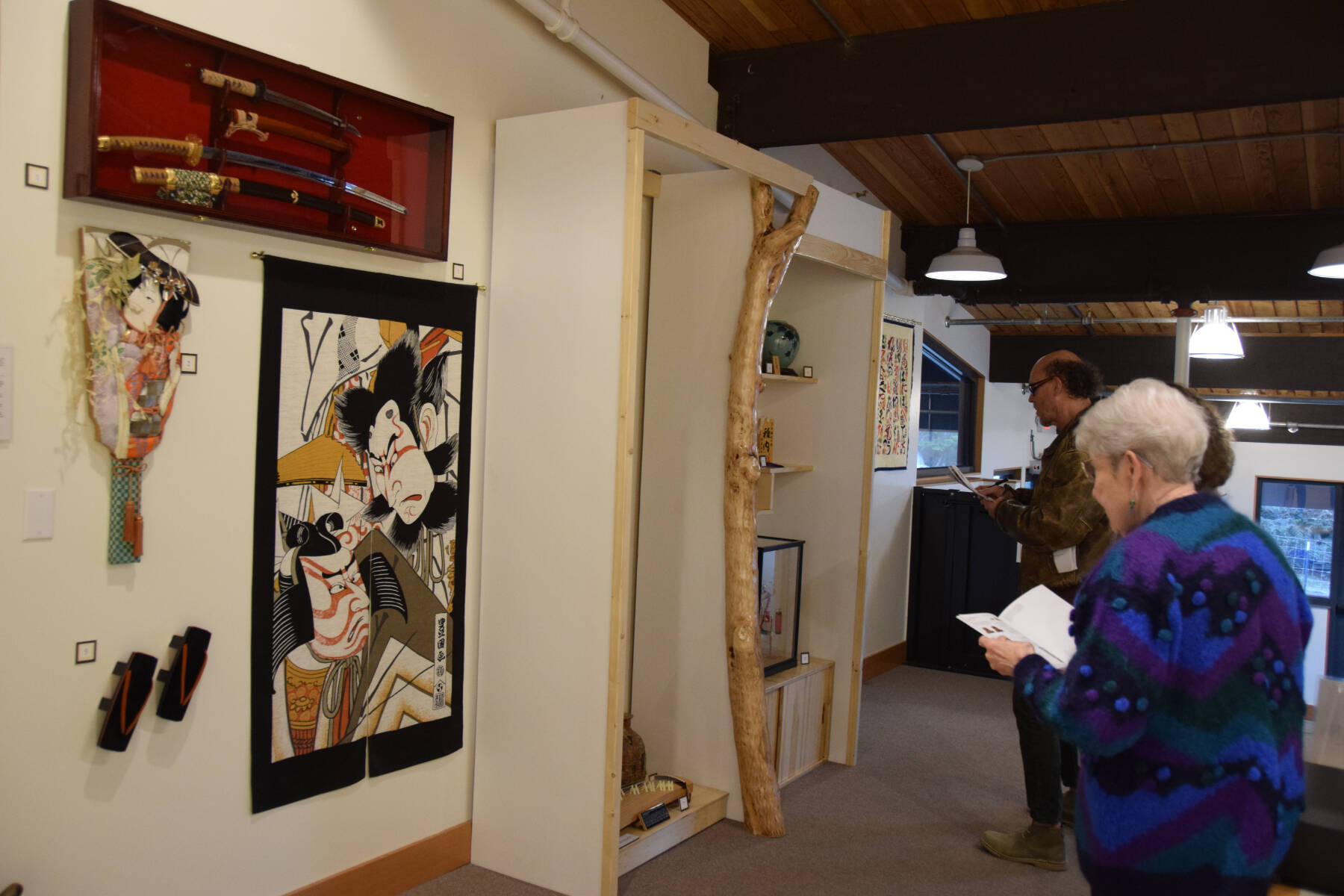 Community members gather at the Pratt Museum on Friday, May 3, 2024 to view art and items donated to Homer by Teshio, Japan, including ceremonial katana, a Hagoita ceremonial racquet, a pair of geta, or traditional wooden sandals, and an Ukiyoe wall hanging depicting kabuki performers, pictured here during the sister city 40th anniversary celebration in Homer, Alaska. (Delcenia Cosman/Homer News)