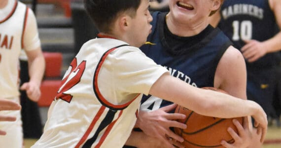 Homer’s Einar Pederson drives on Kenai Central’s Ben Harris on Tuesday, Jan. 21, 2025, at Kenai Central High School in Kenai, Alaska. (Photo by Jeff Helminiak/Peninsula Clarion)