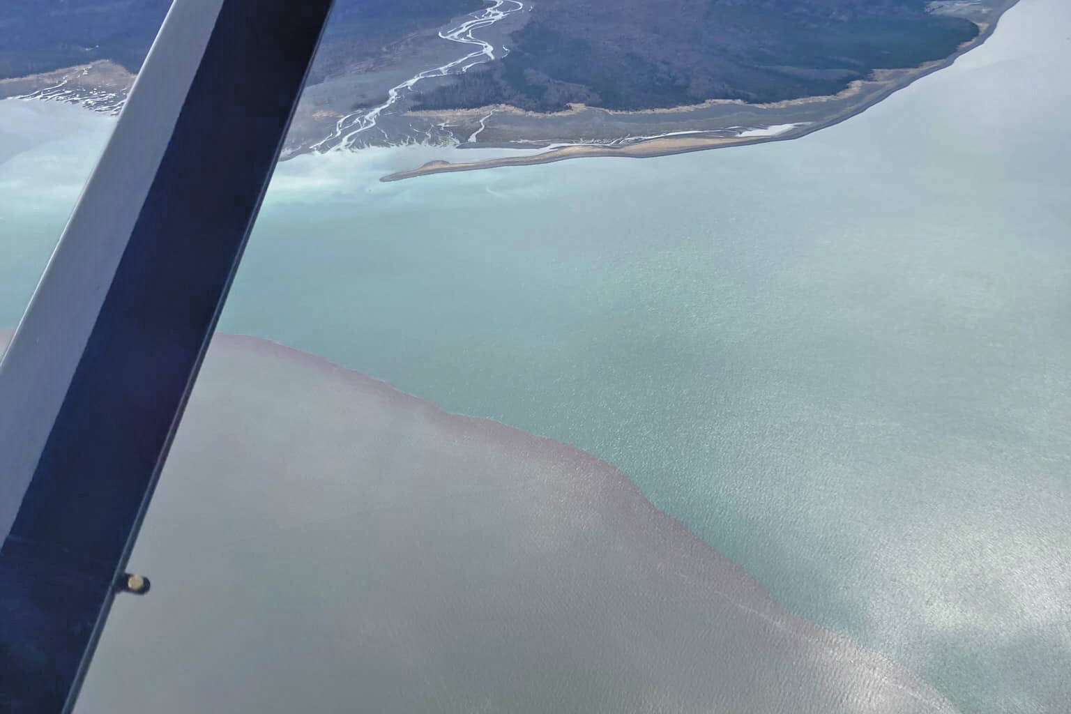 An aerial photo over Grewingk Glacier and Glacier Spit from May 2021 shows a mesodinium rubrum bloom to the left as contrasted with the normal ocean water of Kachemak Bay near Homer. (Photo courtesy of Stephanie Greer/Beryl Air)