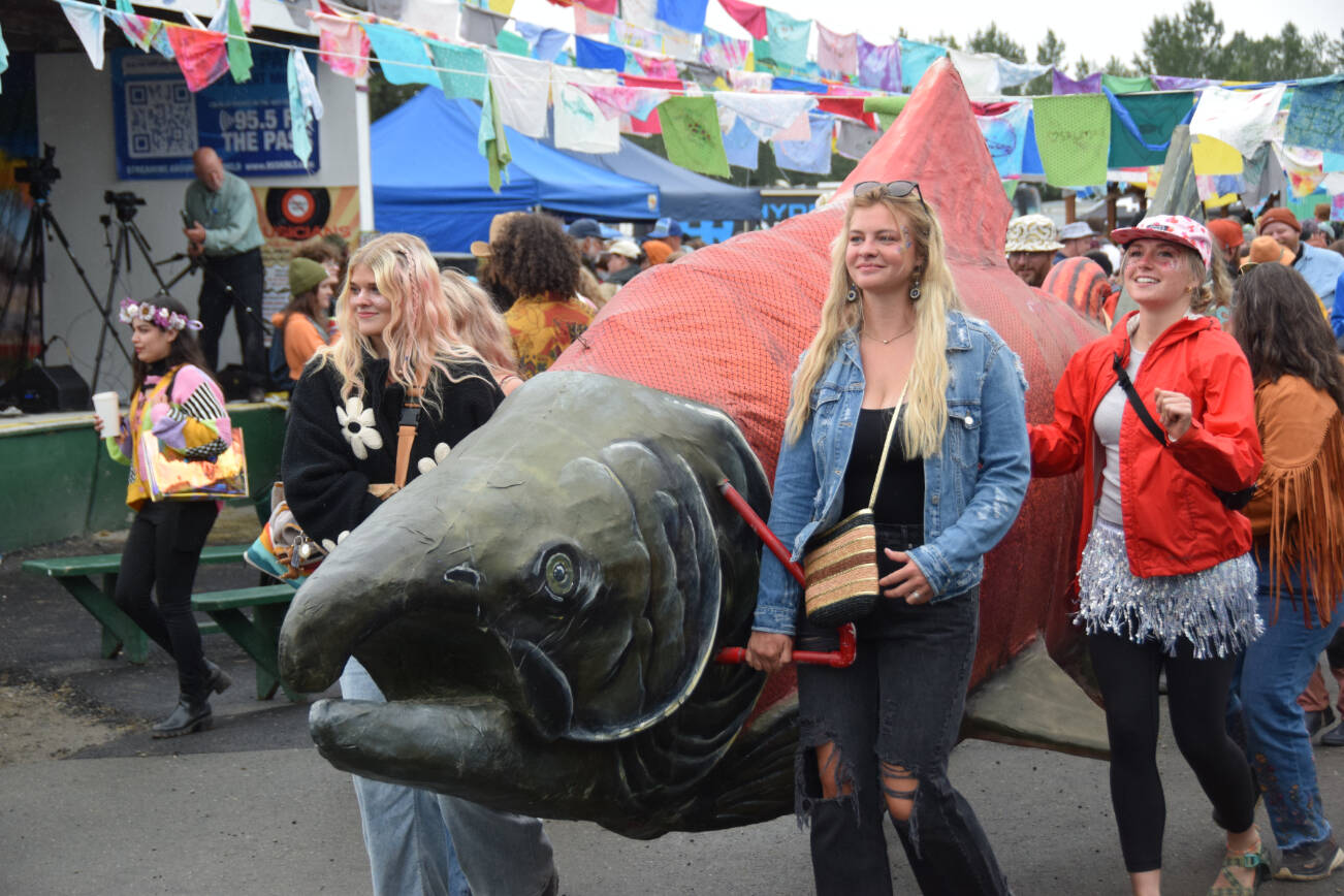Salmonfest attendees accompany the Parkstrippers Marching Band through the Causeway, carrying a large salmon puppet, on Saturday, Aug. 2, 2025, at the Kenai Peninsula Fairgrounds in Ninilchik, Alaska. (Delcenia Cosman/Homer News)