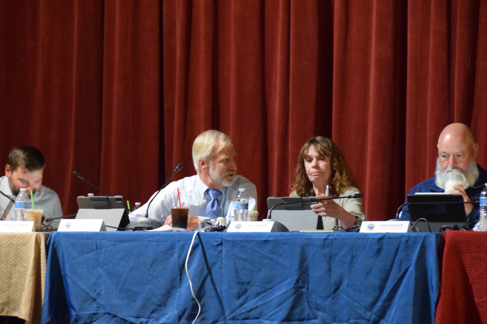 Kenai Peninsula Borough Assembly president, Peter Ribbens, speaks in an aside to District 8 representative and Vice President Kelly Cooper before the beginning of the Aug. 5, 2025, KPB Assembly meeting at the Porcupine Theater in Homer, Alaska. (Chloe Pleznac/Homer News)