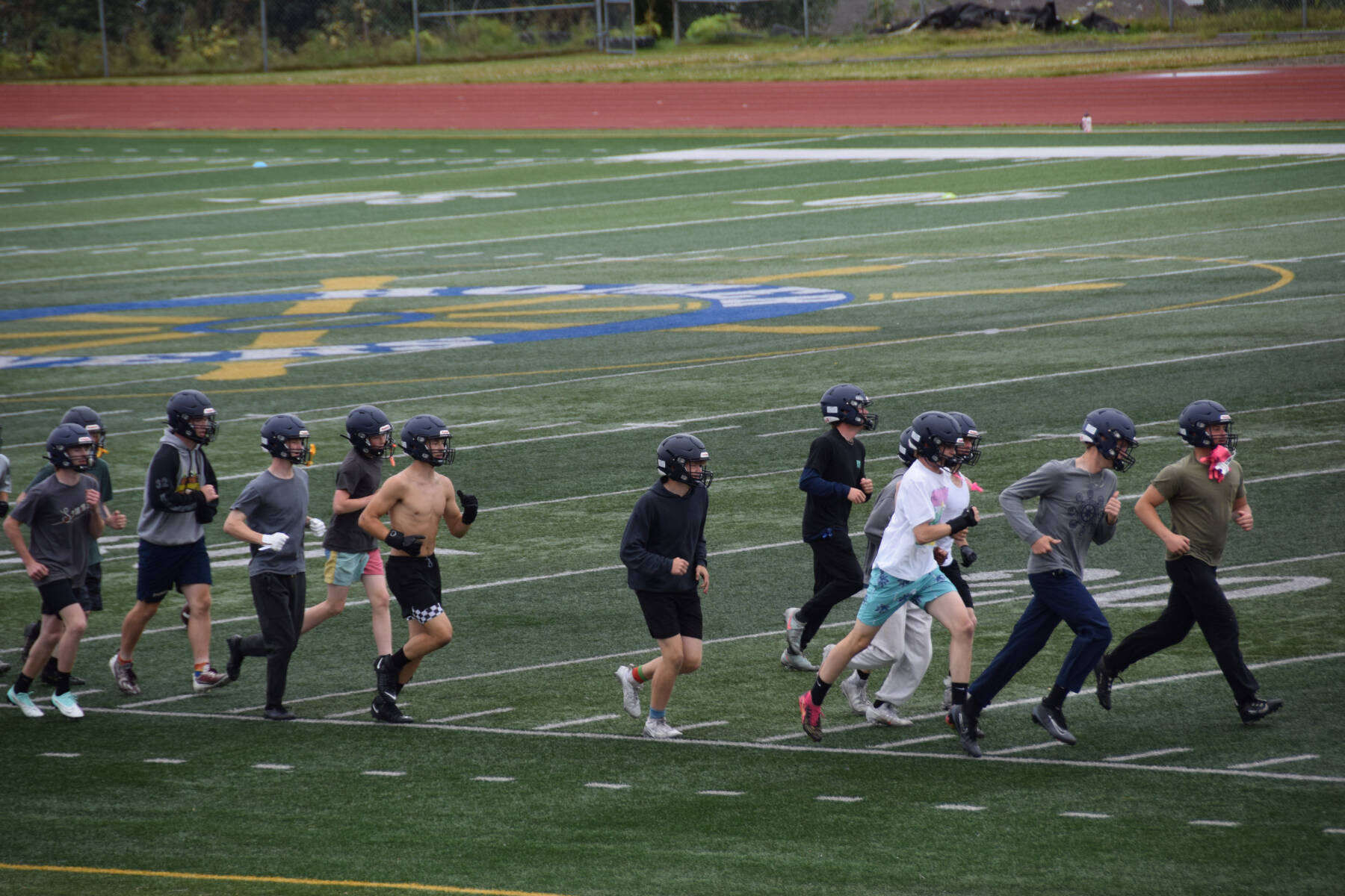 The Homer Mariner football team warms up during practice on Friday, Aug. 8, 2025 on the turf at Homer High School in Homer, Alaska. (Chloe Pleznac/Homer News)