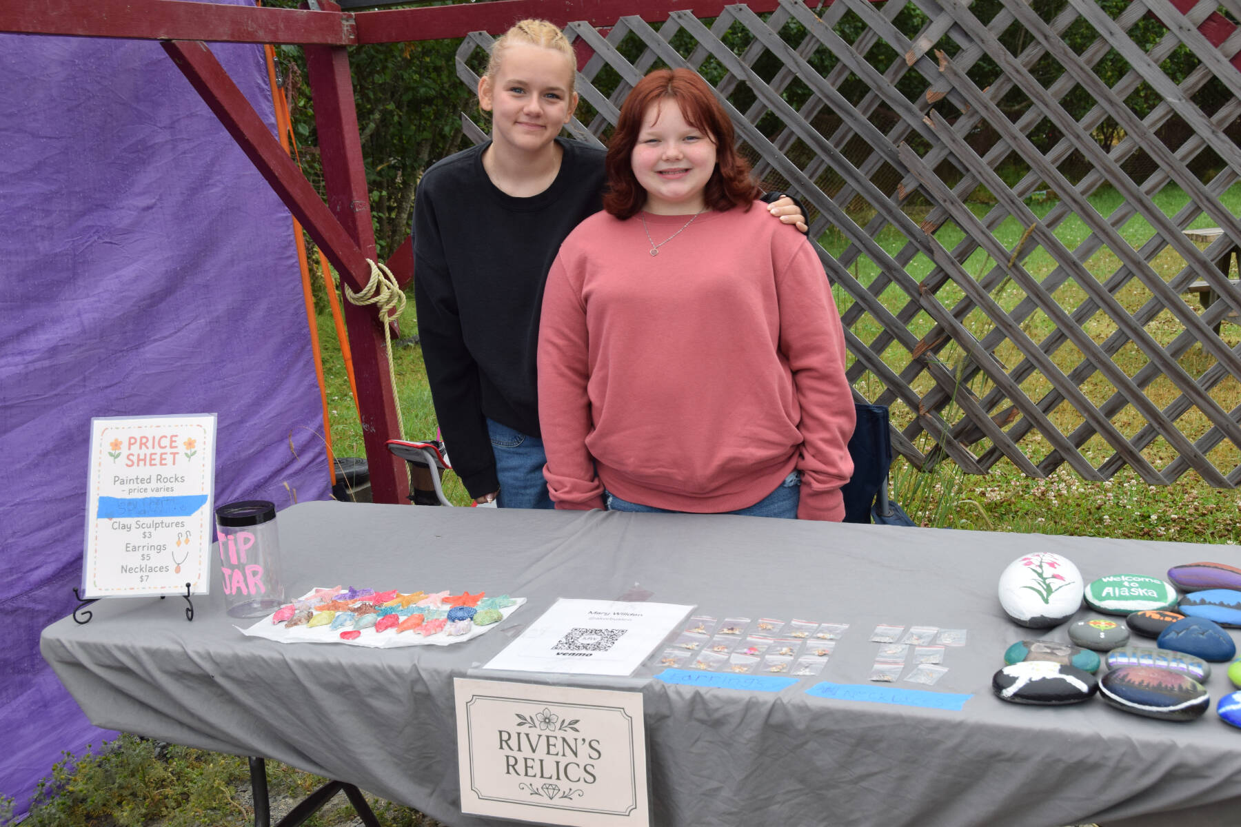 Presley-Riven Willden (right) and Mailea Willden sell painted rocks and other handicrafts at the Homer Farmers Market on Kids’ Vending Day on Wednesday, Aug. 13, 2025, in Homer, Alaska. (Delcenia Cosman/Homer News)