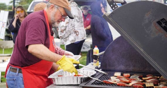 Teague Vanek grills up salmon during the 2025 Industry Appreciation Day at the Kenai Softball Greenstrip in Kenai, Alaska, on Saturday, Aug. 23, 2025. (Jake Dye/Peninsula Clarion)