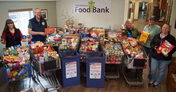 Organizers stand alongside carts filled with food collected during the Freedom from Hunger community food drive at the Kenai Peninsula Food Bank near Soldotna, Alaska, on Friday, Sept. 19, 2025. (Jake Dye/Peninsula Clarion)