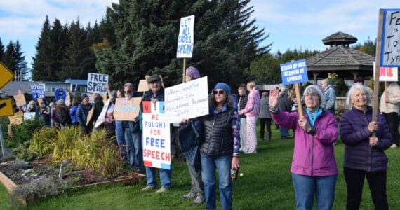 Community members gather and hold signs in support of free speech at a rally on Sunday, Sept. 28, 2025, at WKFL Park in Homer, Alaska. (Delcenia Cosman/Homer News)