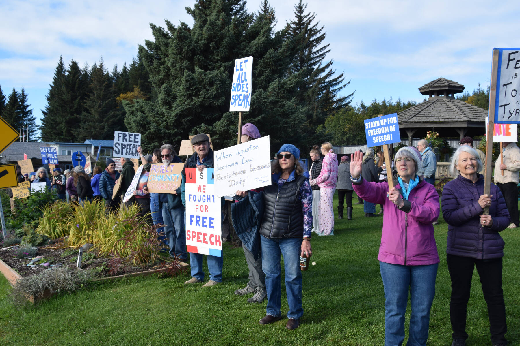 Community members gather and hold signs in support of free speech at a rally on Sunday, Sept. 28, 2025, at WKFL Park in Homer, Alaska. (Delcenia Cosman/Homer News)