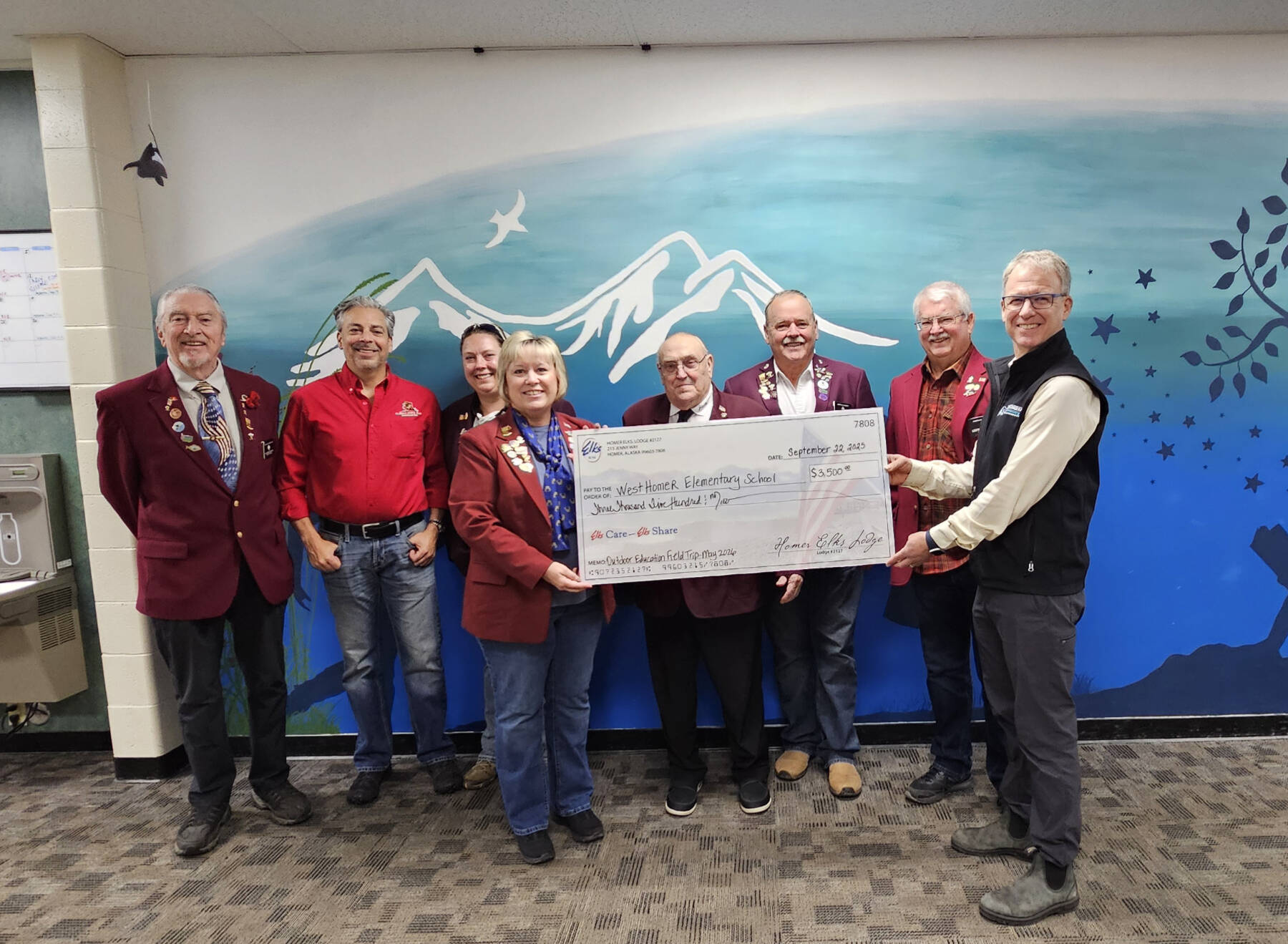 Homer Elks Lodge #2127 Exalted Ruler Jill Hockema (center) and members of the Homer Elks Lodge donate $3,500, using grant funds received, to West Homer Elementary School in Homer, Alaska, on Sept. 22, 2025, to provide fourth-grade students the opportunity to participate in the annual Outdoor Education Field Trip scheduled for May 2026. Photo provided by Jill Hockema