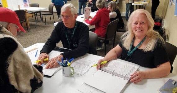 Election workers Susie Myhill (right) and Charlie Franz help voters before they cast their ballots on Election Day, Tuesday, Oct. 7, 2025, in the Homer City Hall Cowles Council Chambers in Homer, Alaska. (Delcenia Cosman/Homer News)