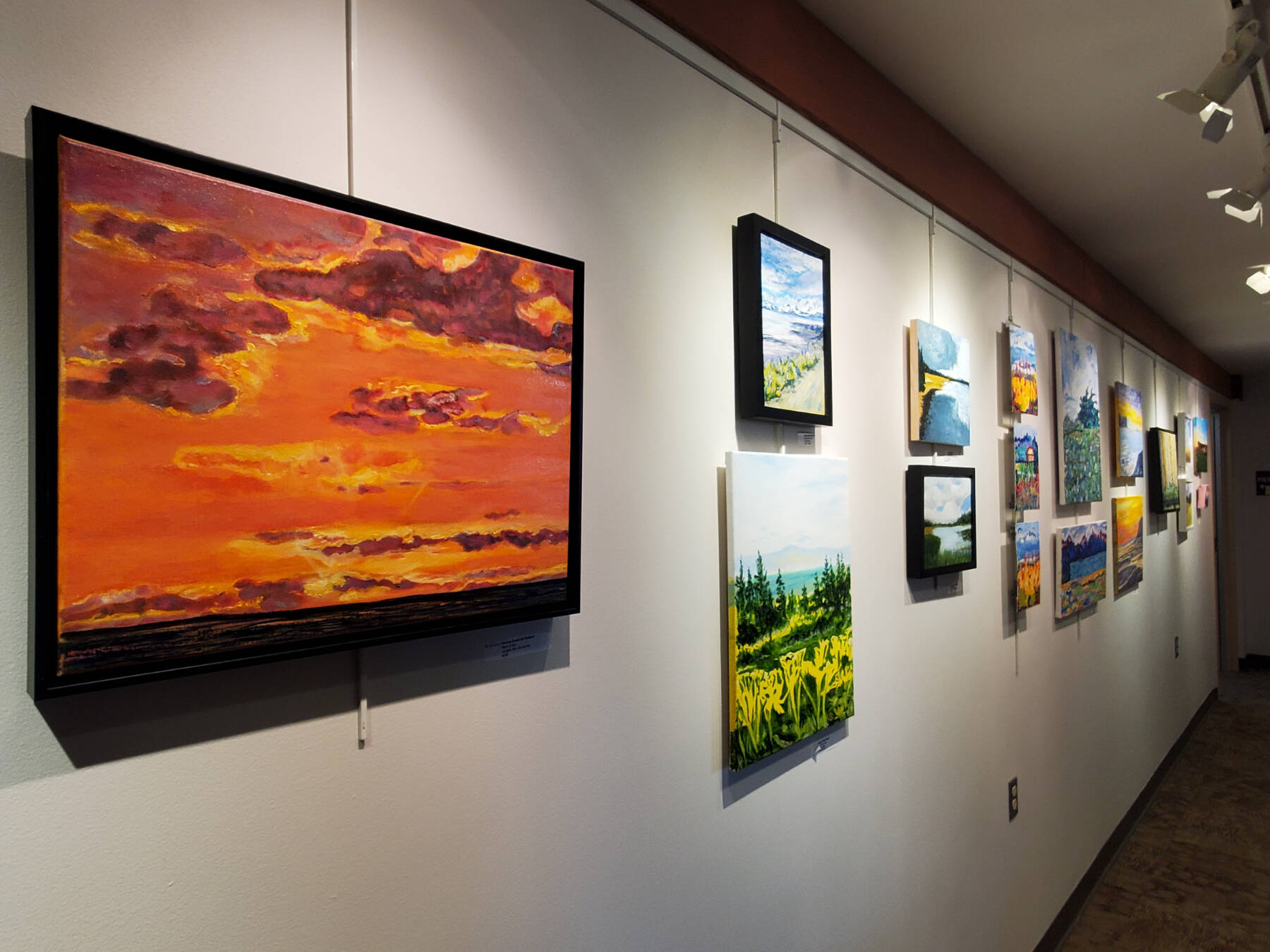 Artwork from a summer painting workshop is on display on the gallery wall in Kachemak Bay Campus’s Pioneer Hall on Saturday, Oct. 18, 2025, in Homer, Alaska. (Delcenia Cosman/Homer News)