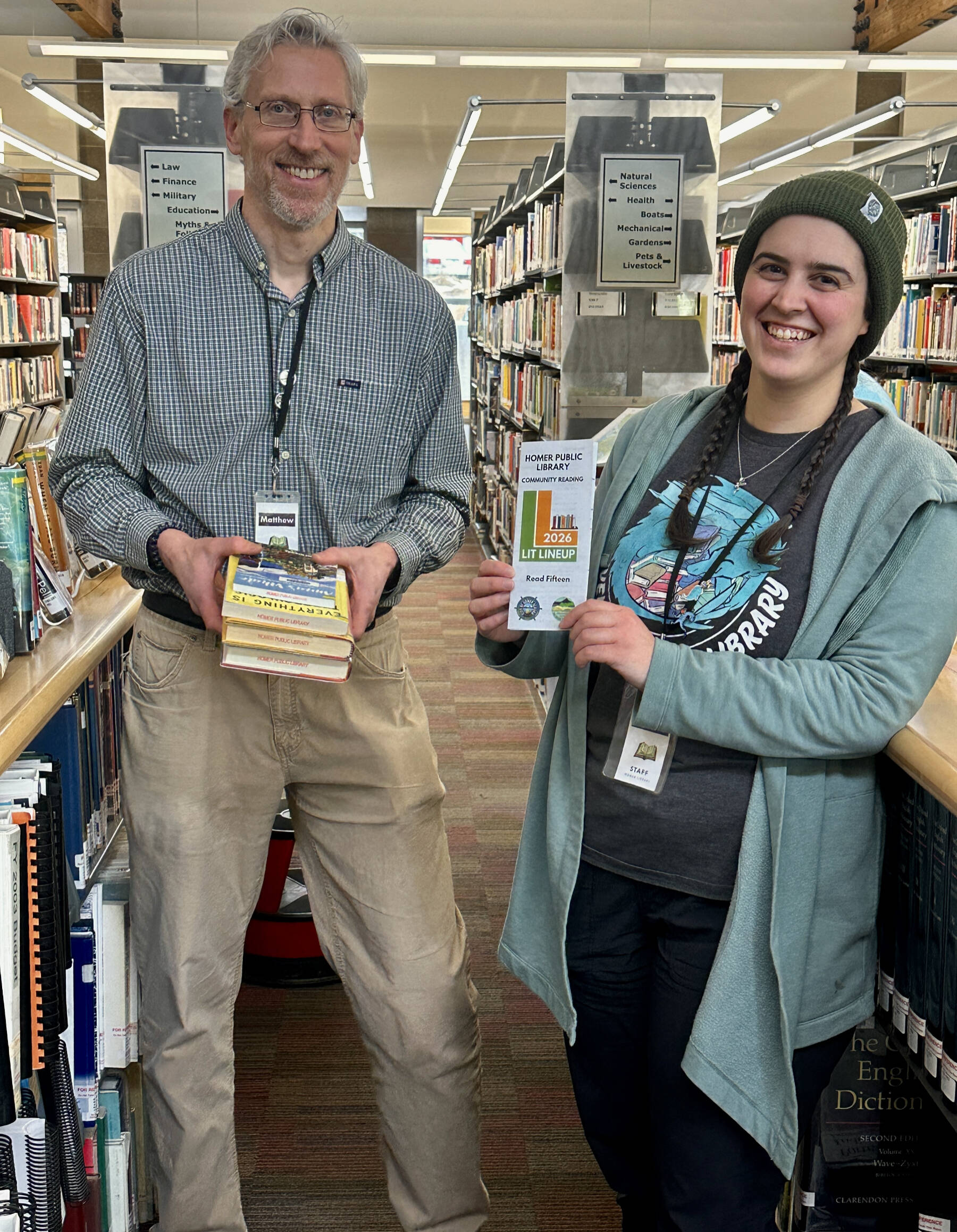 Homer Public Library Technician and Lit Lineup coordinator Matthew Smith (left) and Library Technician Regina Johanos are photographed with this years Lit Lineup books and reading list on Friday, Jan. 23, 2026, in Homer, Alaska. Photo by Christina Whiting