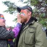 Sage Anderson applies Pride-themes paint to Jack Dozier-Zizkas face before Homers first Pride March on Saturday, June 23, 2018 at WKFL Park in Homer, Alaska. Participants gathered there to get ready and make signs before heading out on the march from the park to Grace Ridge Brewery. (Photo by Megan Pacer/Homer News)