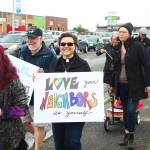 Lisa Talbot, a pastor at Homer United Methodist Church, walks along Pioneer Avenue during Homers first Pride March with a sign that reads Love your neighbors as yourself on Saturday, June 23, 2018 in Homer, Alaska. (Photo by Megan Pacer/Homer News)