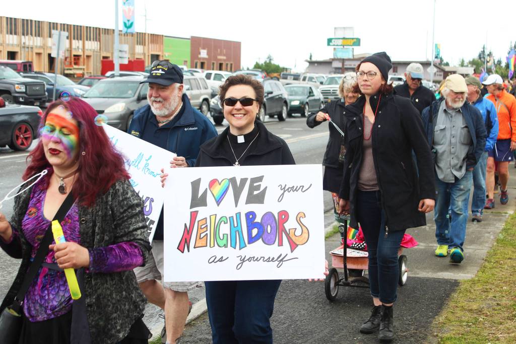 Lisa Talbot, a pastor at Homer United Methodist Church, walks along Pioneer Avenue during Homers first Pride March with a sign that reads Love your neighbors as yourself on Saturday, June 23, 2018 in Homer, Alaska. (Photo by Megan Pacer/Homer News)