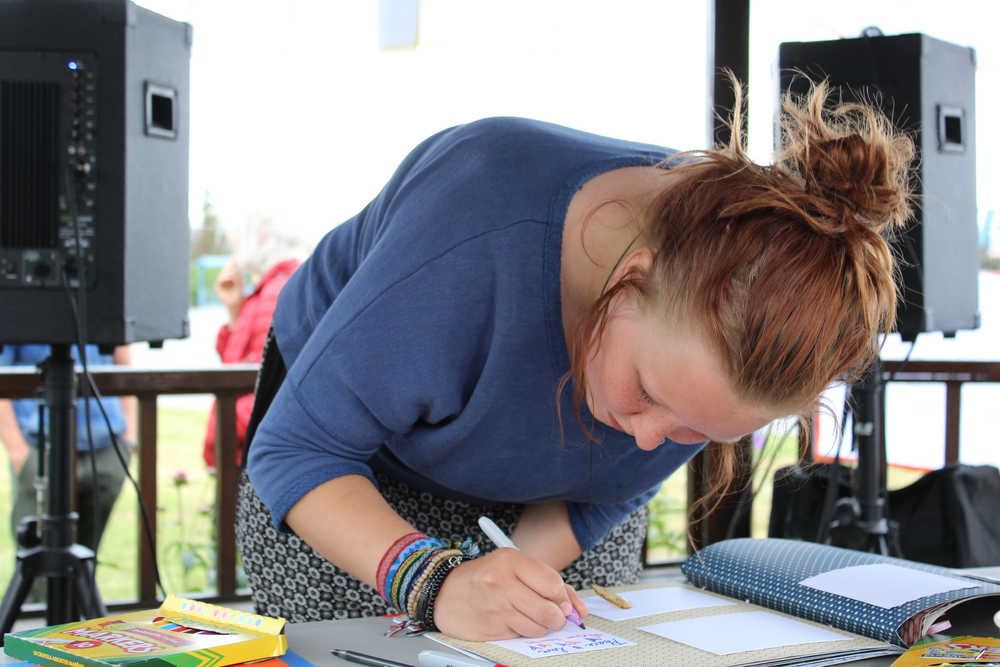 Laurel Glaves, a sophomore at Homer High School, writes words of support to the Orlando, Fla. LGBTQ community in a book during the Love for Orlando event at WKFL Park on Friday, June 17. "I heard about what happened and my friends had a moment of silence and cried for a little," Glaves said. "It's really beautiful seeing the Homer community coming together."