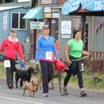 Kelsey Beecher, 24, and Ashley Pagni, 32, of Anchorage and Erin Thomson, 30, of Homer walk their dogs along the Spit towards the finish line of the Spit Run on Saturday, June 25.