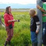 Carmen Field, a marine science educator with the Kachemak Bay Research Reserve, speaks during an Estuary Walk tour in July 2011. Field holds up a handful of mud, or detritus, dug from the estuary. "This is the bottom of the ocean food chain," she said.-Homer News file photo