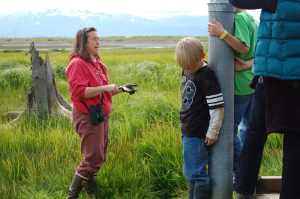 Carmen Field, a marine science educator with the Kachemak Bay Research Reserve, speaks during an Estuary Walk tour in July 2011. Field holds up a handful of mud, or detritus, dug from the estuary. "This is the bottom of the ocean food chain," she said.-Homer News file photo