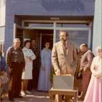 Hospital staff and local and state officials gather to celebrate the grand opening of the South Peninsula Hospital's new location on Bartlett Street in 1977. Helen Alm, a nurse who worked in the hospital's first location, starting in the 1950s, looks on from the entrance in a white nurse's uniform. The new hospital opened on July 1 with 17 beds and is at the same location that the hospital is located today.