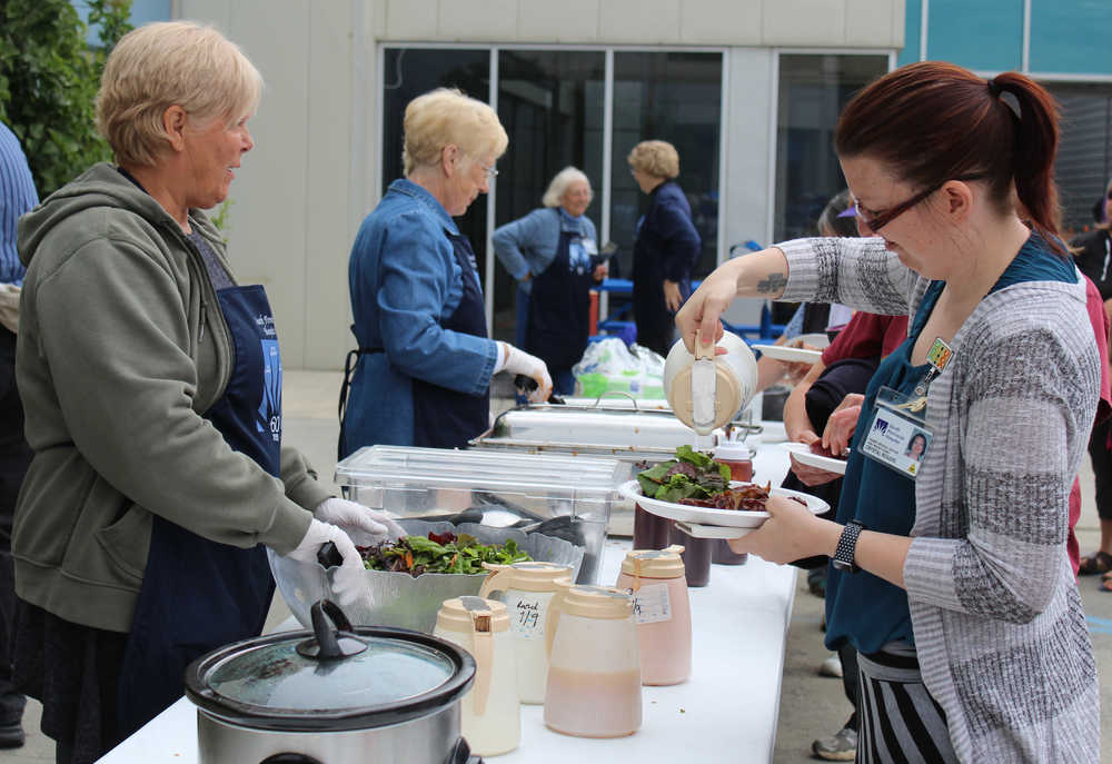 Homer Medical Center employee Crystal Rogers pours dressing over the salad accompanying the ribs on her lunch plate at the South Peninsula Hospital 60th Anniversary Party. Black Jaxx BBQ provided lunch for attendees of the Saturday, July 9 celebration.