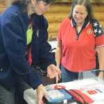 Samantha Cunningham, left, shows Bobby News how to work an automatic external defibrilator at the Anchor Point Senior Center. Cunningham is the Kenai Peninsula Borough Emergency Medical Services coordinator and Ness is president of the senior center board. Cunningham helped get a $43,000 grant from the Tesoro Foundation to install AEDs in public places on the peninsula, including Anchor Point.-Photo by Michael Armstrong, Homer News
