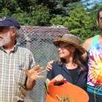 Wayne Jenkins, along with Lori Jenkins and Alex Folio, explains the activities available to guests in the afternoon at Synergy Gardens' First Annual Great Garlic Scape Festival. Folio lead a group in a yoga flow, while Wayne guided a farm tour, and others took part in making botanical art.