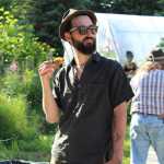 Max Doyle looks out at the other festival goers in between bites of pizza. Wood-fired pizza featuring local produce was served for dinner at the First Annual Great Garlic Scape Festival at Synergy Gardens.