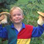 Neil McArthur and Harriette Parker's son Colin McArthur shows off two King Boletees in 1994, when he was about 5 years old. Colin was in on preparation for the 1994 edition of Alaska's Mushrooms at an early age and it influenced him later, Neil said. Colin lives in Portland, Ore. and is part of the band Animal Eyes, which plays in Homer every year. One of their songs is called "Mushroom Hunter."-photo provided