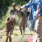 Conrad Field hoses down his daughter Eryn Field after she covered herself in mud at the 2016 Mud Wallow at Cottonwood Park on July 17.
