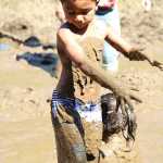 Zaine Beckworth looks down at the mud covering him as he wades through the mud pit at the 2016 Mud Wallow at Cottonwood Park on July 17.