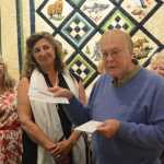 Jack Regan, president of Patrons of the Pratt, or POPS, on Tuesday night presents Pratt Museum Board President Sara Jackinsky with two checks totalling $425,000 - the balance of a pledge POPS made in 2011 to raise $500,000 for the museum's capital construction fund. POPS had earlier donated $75,000 to help with design of the museum's proposed new building. Members of POPS, including past board presidents, attended the ceremony. Regan presented the checks in front of this year's quilt to be raffled, one of the ways POPS raises funds.