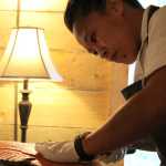 Aisha Ibrahim, a chef at Tutka Bay Lodge for the 2016 summer season, runs her knife along the backbone of the salmon to create a filet with one clean cut. -Photo by Anna Frost, Homer News