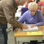 Steve Gibson, left, points to his name on the voter rolls at Homer City Hall to poll worker Mariann Lyda.