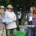 Paul and Jen Castellani smile as Denise Jantz of Kachemak Heritage Land Trust and Coowe Walker of Kachemak Bay Research Reserve present them with the King Maker award for their care for their land, which has a stream with baby salmon in it. Walker reads a letter from KHLT explaining why the Castellanis are deserving of the King Maker award.