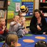 8:30 a.m.: After reading, Anne Love leads the kids in a name game in which the person holding a stuffed bumble bee says their name and then the class says the name back three times: first outloud, then as a whisper, and then spelled out while clapping. Love also went over more classroom and school rules with the class, framing the exercise by telling the class she was new too and asking if they could tell her some of the rules they knew.