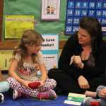10:53 a.m.: Before lunch, the class plays a reading game. Anne Love shows Faither Overson a sight word flashcard to read aloud to the class. Leya and Maxim Sanarov look on as Faith reads. After she took them to lunch, her day at McNeil Canyon Elementary is over as she is currently a half-time teacher and her class goes to afternoon lessons with another teacher.