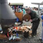 John Miles feeds the wood stove at the Kachemak Bay Wooden Boat Festival last Saturday. Miles volunteers every year to help build the blanks for children to make their own wooden boats.