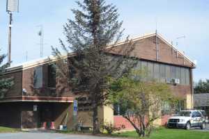 The front entrance and parking lot to the Homer Police Station on Heath Street downhill from Homer High School.