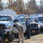 Alaska State Trooper Sgt. Dan Cox, center, examines a crashed truck at Northern Enterprises Boat Yard on Thursday afternoon. Paul Suter, 30, is accused of stealing the truck and evading troopers and Homer Police in a high-speed chase from Anchor Point to Homer. Police caught Suter after he crashed the truck. Troopers said Suter ran from the truck holding a gallon jug of Scotch whisky, seen here on the hood of a trooper vehicle. He's also charged with two counts of driving under the influence.