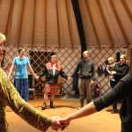 Pegge Paver looks toward her neighbor as a group prepares to contra dance in a yurt at Ageya Wilderness Center as part of the Homer Folk School grand opening event on Saturday, Oct. 8.