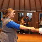 Robin McAllistar, board member of the Homer Folk School, takes a neighbors hand during contra dance at the folk school's grand opening event on Saturday, Oct. 8.
