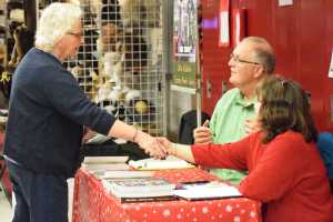 Photo by Megan Pacer/Peninsula Clarion Mike Chihuly and his wife, Shirley, greet a passerby while he signs copies of his recently published book, "Alaska Fish and Fire," on Saturday, Nov. 26, 2016 at the annual Peninsula Art Guild's Fine Arts and Crafts Fair.