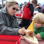 Left, mother and son boat-building team Amy and Elias Sundheim put finishing touches on a sailboat at the festival on Sunday.-Photo by McKibben Jackinsky,  Homer News