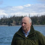 King Harald V poses for a photograph on the stern of the Rainbow Connection as it travels through Kachemak Bay on Tuesday morning.-Photo by Michael Armstrong; Homer News
