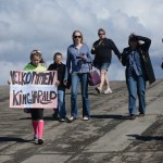 Carly Johnson carries a sign that reads "Welcome, King Harald," at the Homer Harbor on Tuesday morning.-Photo by Michael Armstrong; Homer News