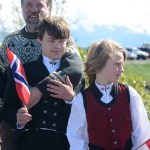 Mark Restad, back, stands with his sons Espen, left, and Leif, right, as they wait to greet King Harald V at the Homer Harbor on Tuesday morning. The boys wear traditional Norwegian "bunad" clothing.-Photo by Michael Armstrong; Homer News