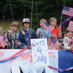 Kids wave from the back of a pickup truck for the Ocean Shores Motel float.-Photo by Michael Armstrong, Homer News