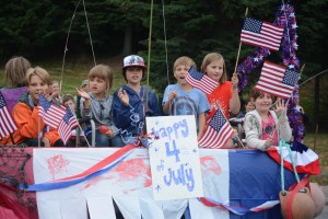 Kids wave from the back of a pickup truck for the Ocean Shores Motel float.-Photo by Michael Armstrong, Homer News